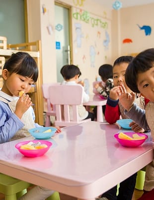 three toddler eating on white table